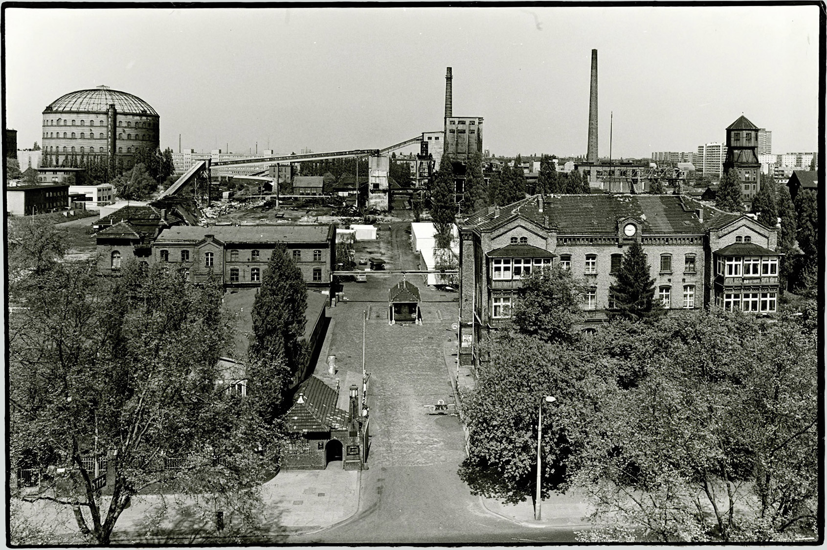 Die Hauptzufahrt zum Werksgelände an der Danziger Straße um 1982. Die Gebäude im Vordergrund sind die einzig erhaltenen. Sie werden seit 1986 und bis heute als kulturelle Einrichtungen genutzt. Links im Hintergrund eines der drei Gasometer.