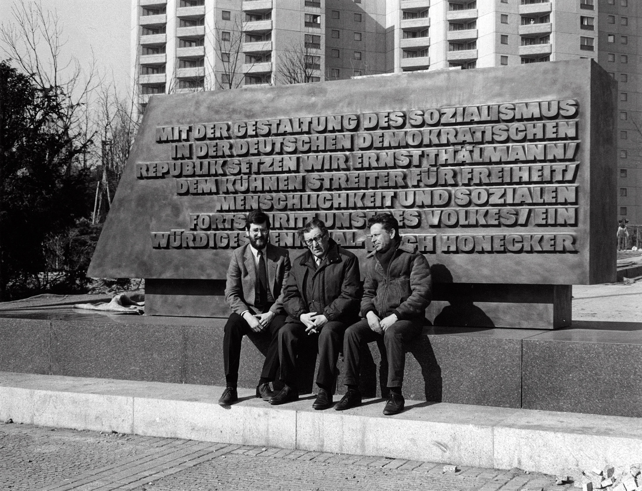 Der Bildhauer Lew Kerbel (Mitte) vor der Bronzestele mit der Inschrift von Erich Honecker